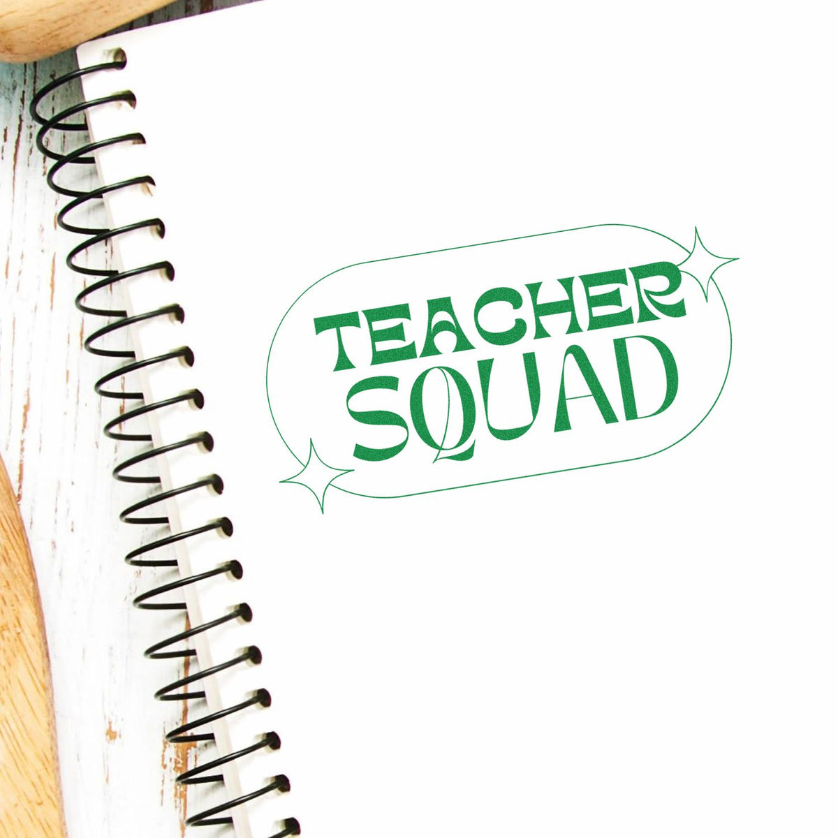 Green Teacher Squad green stamp seal on a white notebook page with black spiral binding and sparkle accents.