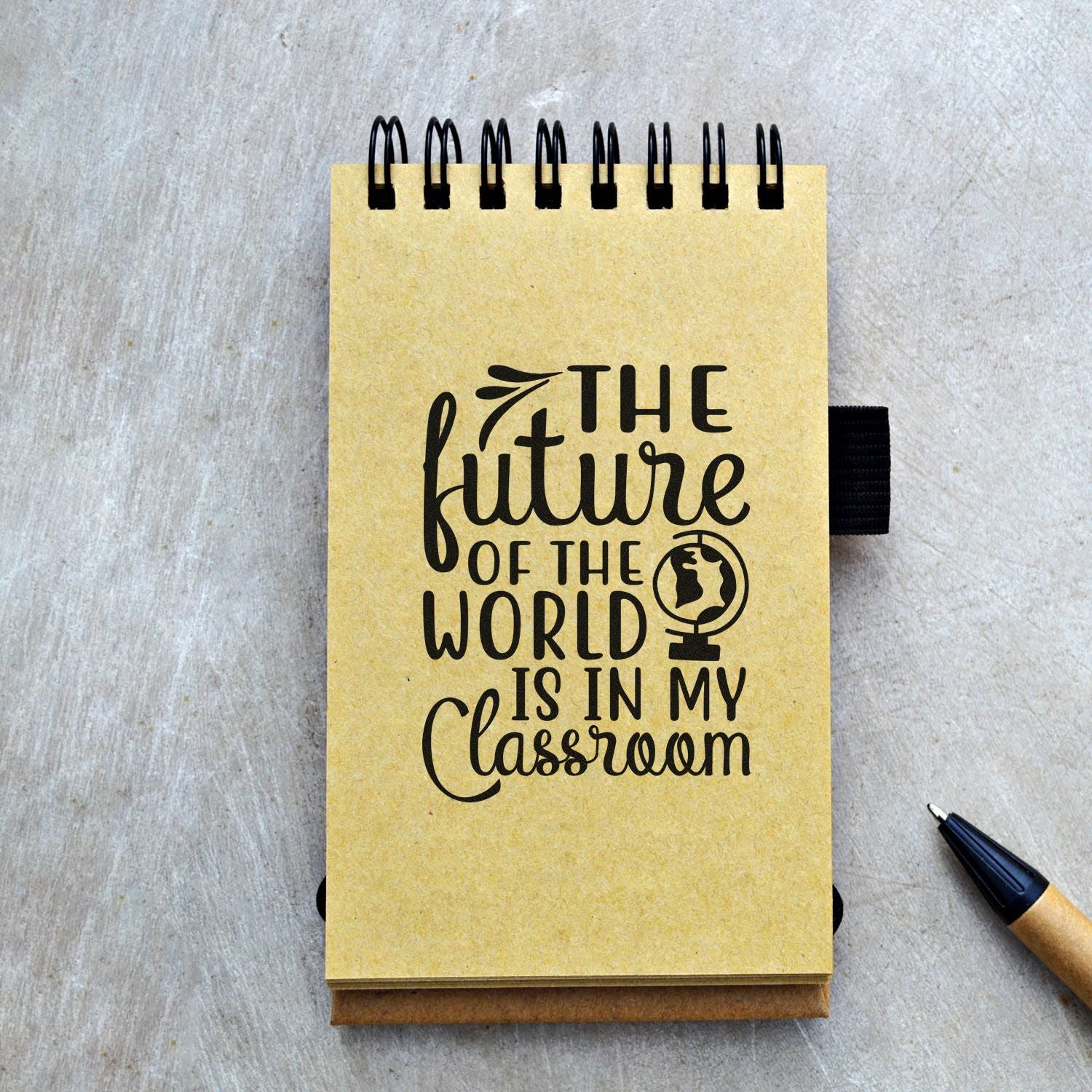 Yellow spiral notebook stamp design with black The future of the world is in my classroom text and globe icon.