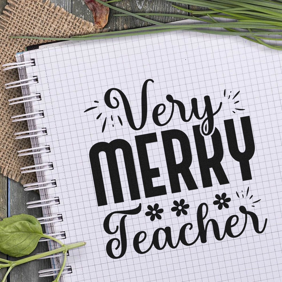 Black Very Merry Teacher holiday stamp and seal design on white grid paper with floral accents and green leaves.