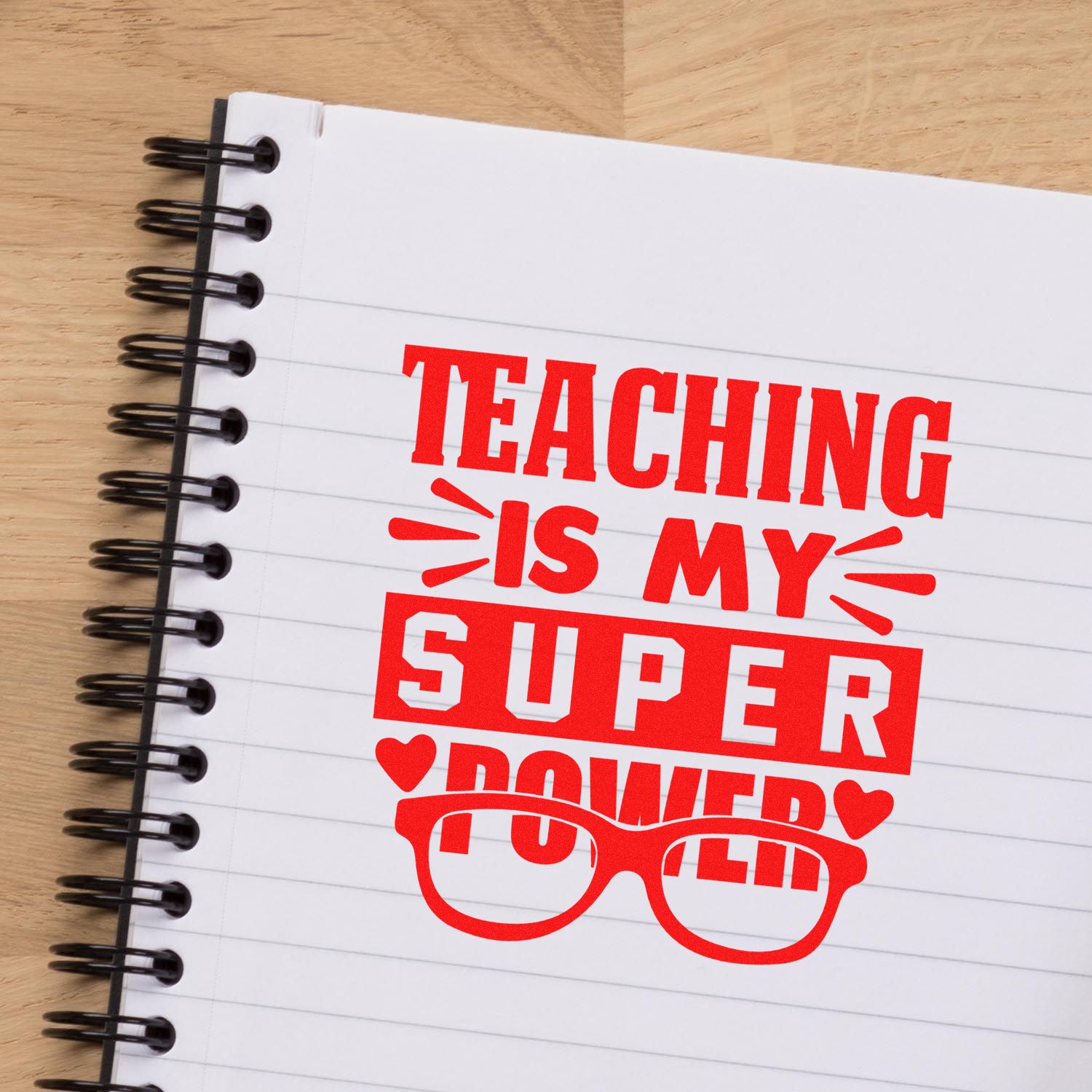 Red teaching stamp and seal design on a white spiral notebook, with bold red text and glasses icon on a wood desk.