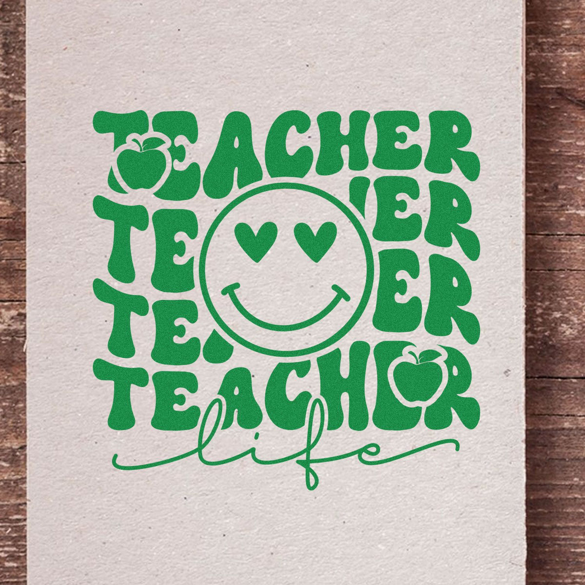 Green teacher life stamp design with smiley face, hearts for eyes, and apple icons on cream paper.