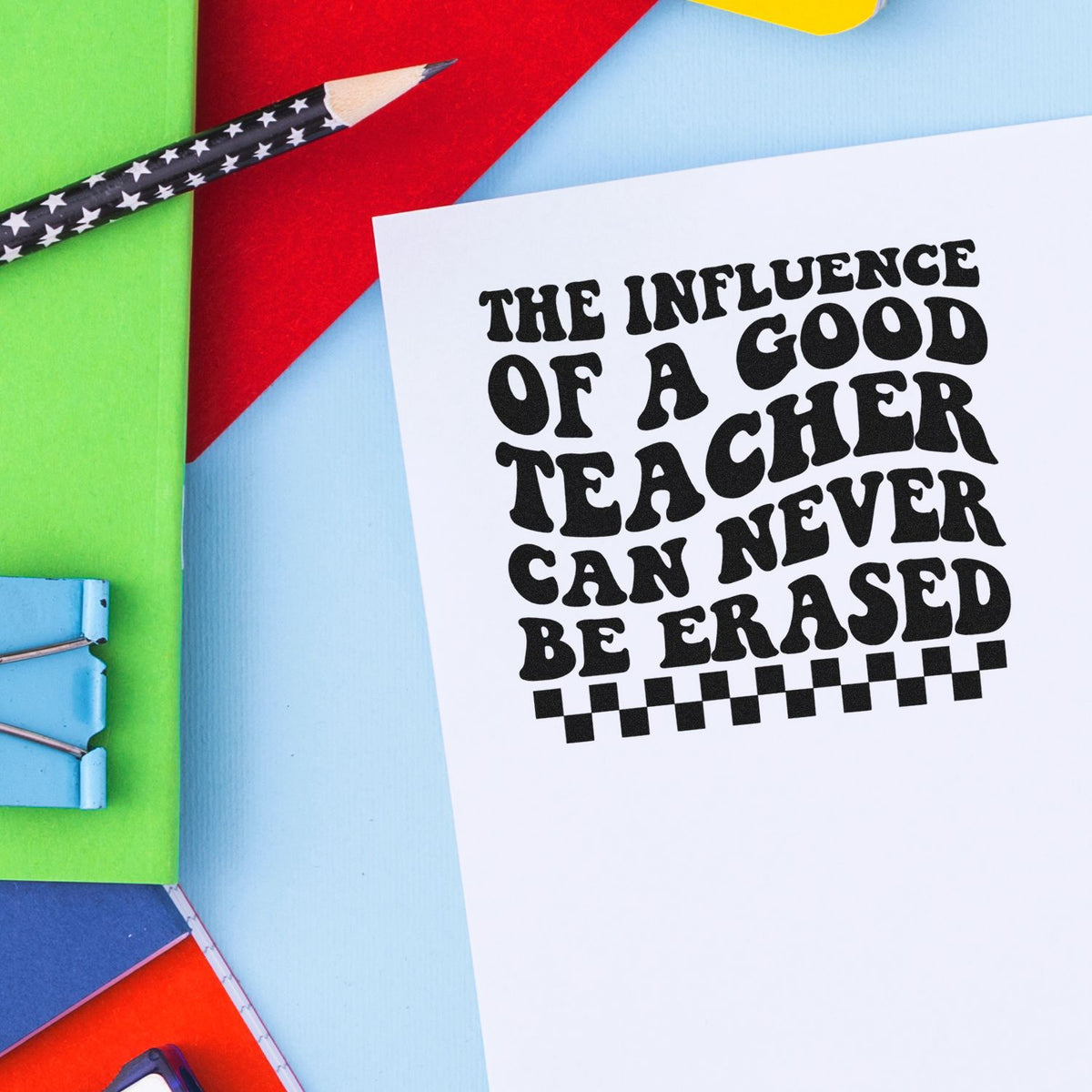 Black rubber stamp/seal reading The influence of a good teacher can never be erased on white paper, with colorful stationery.