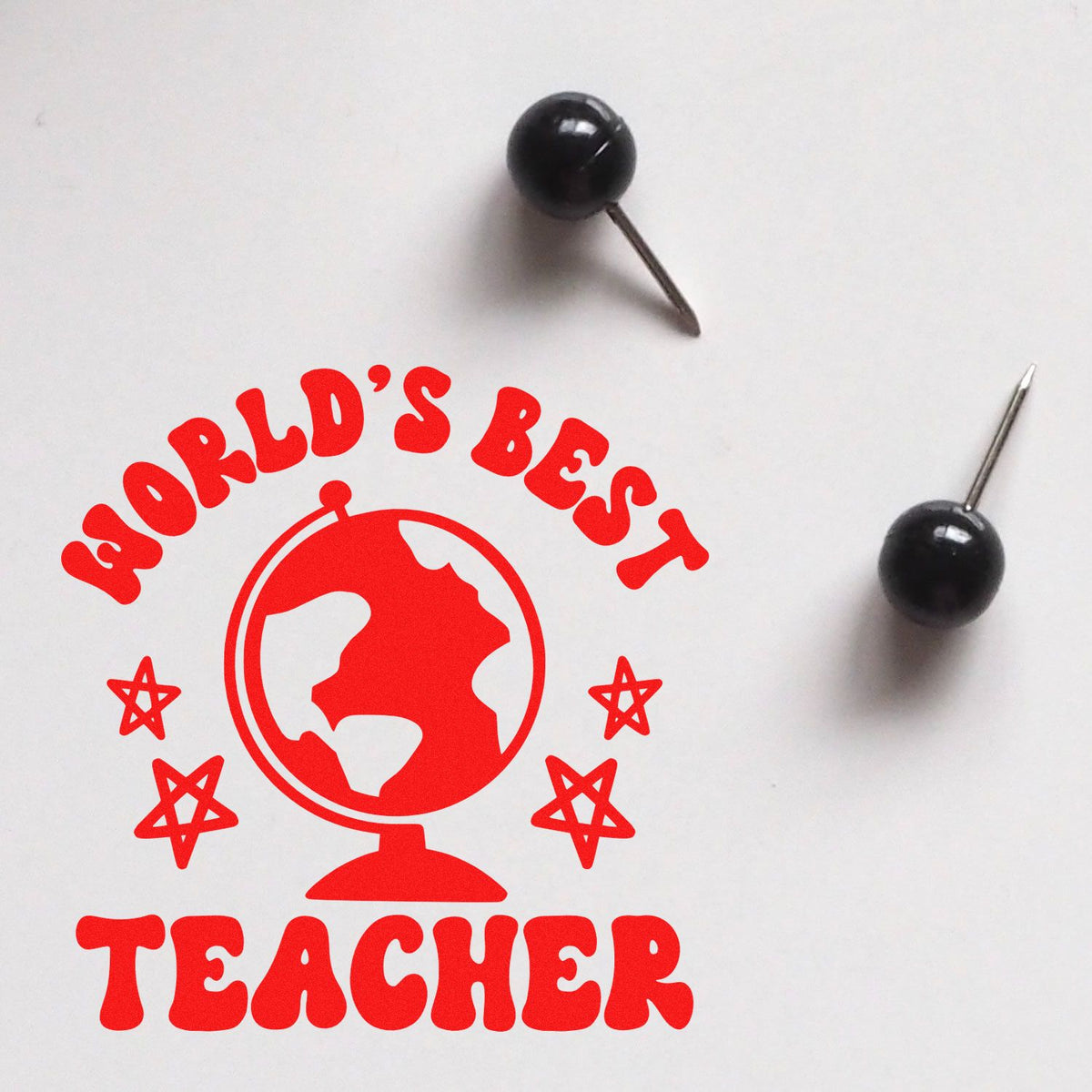 Red World's Best Teacher rubber stamp design with globe and stars, plus two black seal pins on a white background.