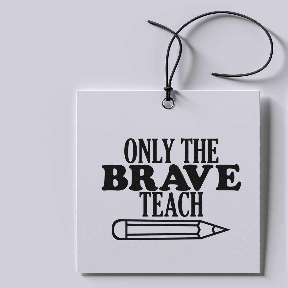White stamp seal tag with black cord, bold black Only the Brave Teach text and pencil icon.