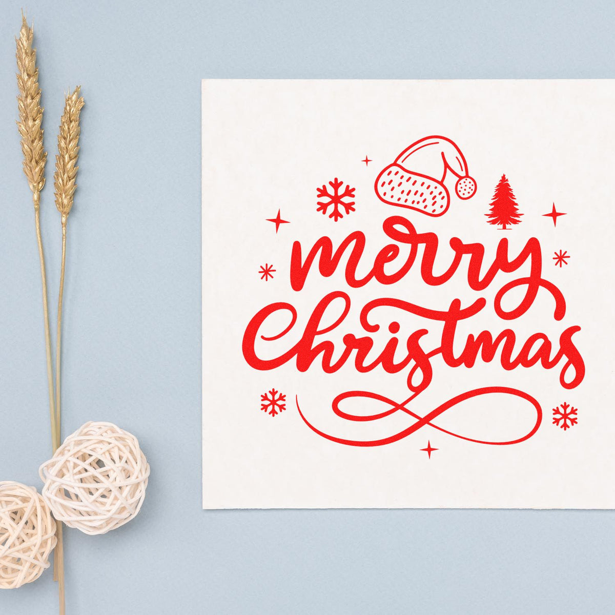 Red Merry Christmas stamp seal on white card with Santa hat, snowflakes and pine tree, on pale blue background.