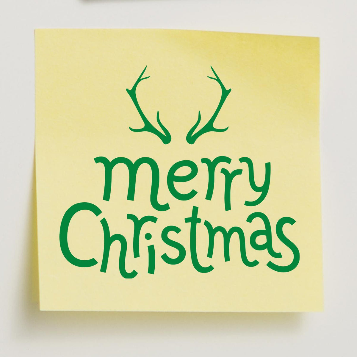 Green Merry Christmas stamp and seal design with antlers on a pale yellow square background.