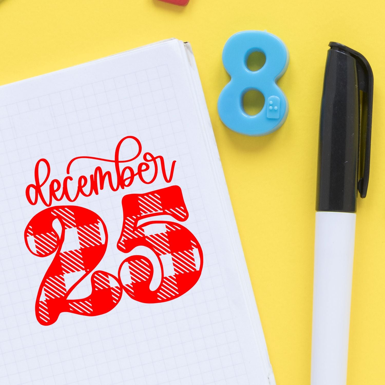 Red December 25 stamp on grid notebook with blue number 8 seal and black-and-white marker on yellow background