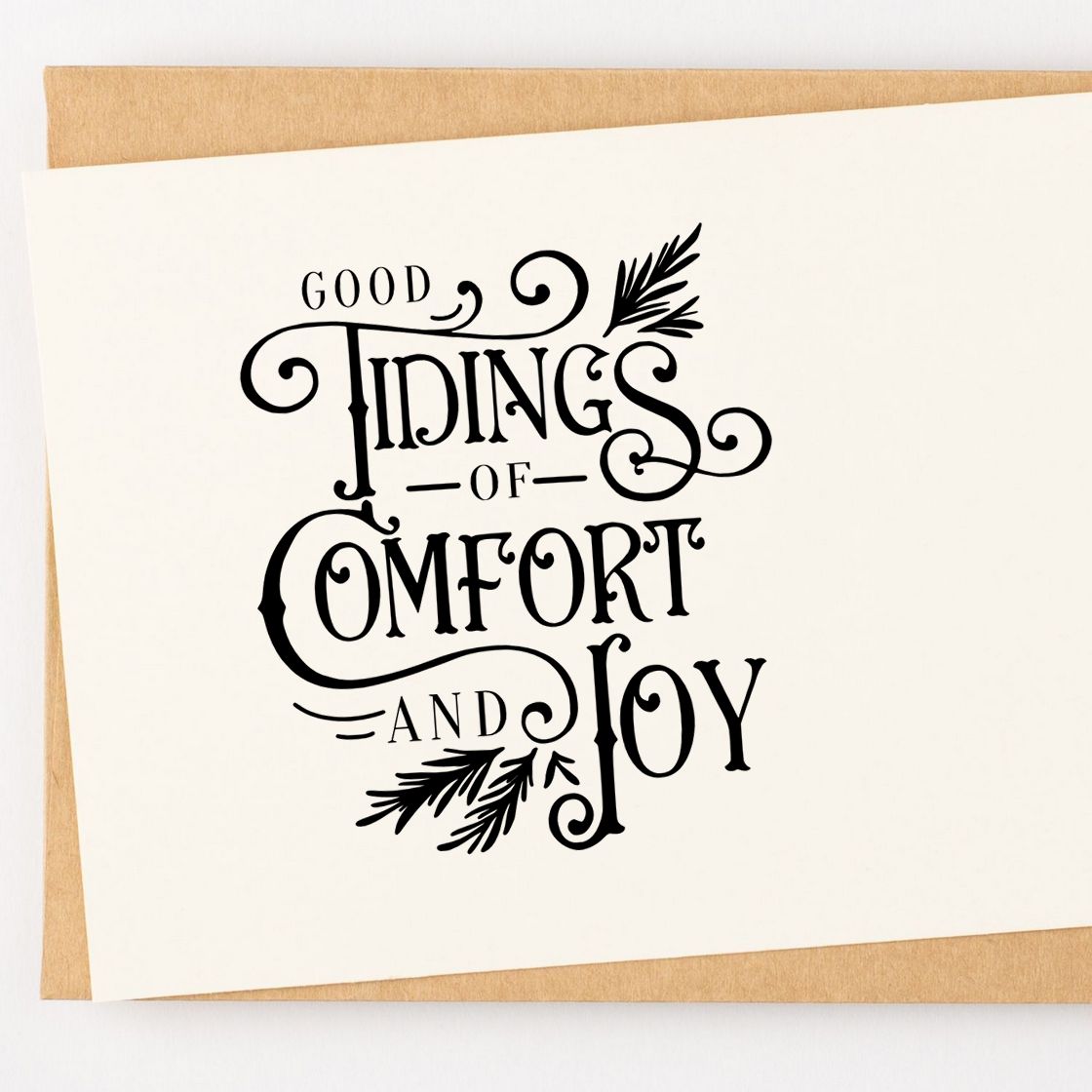 Black decorative stamp/seal reading Good Tidings of Comfort and Joy on cream card with tan envelope.