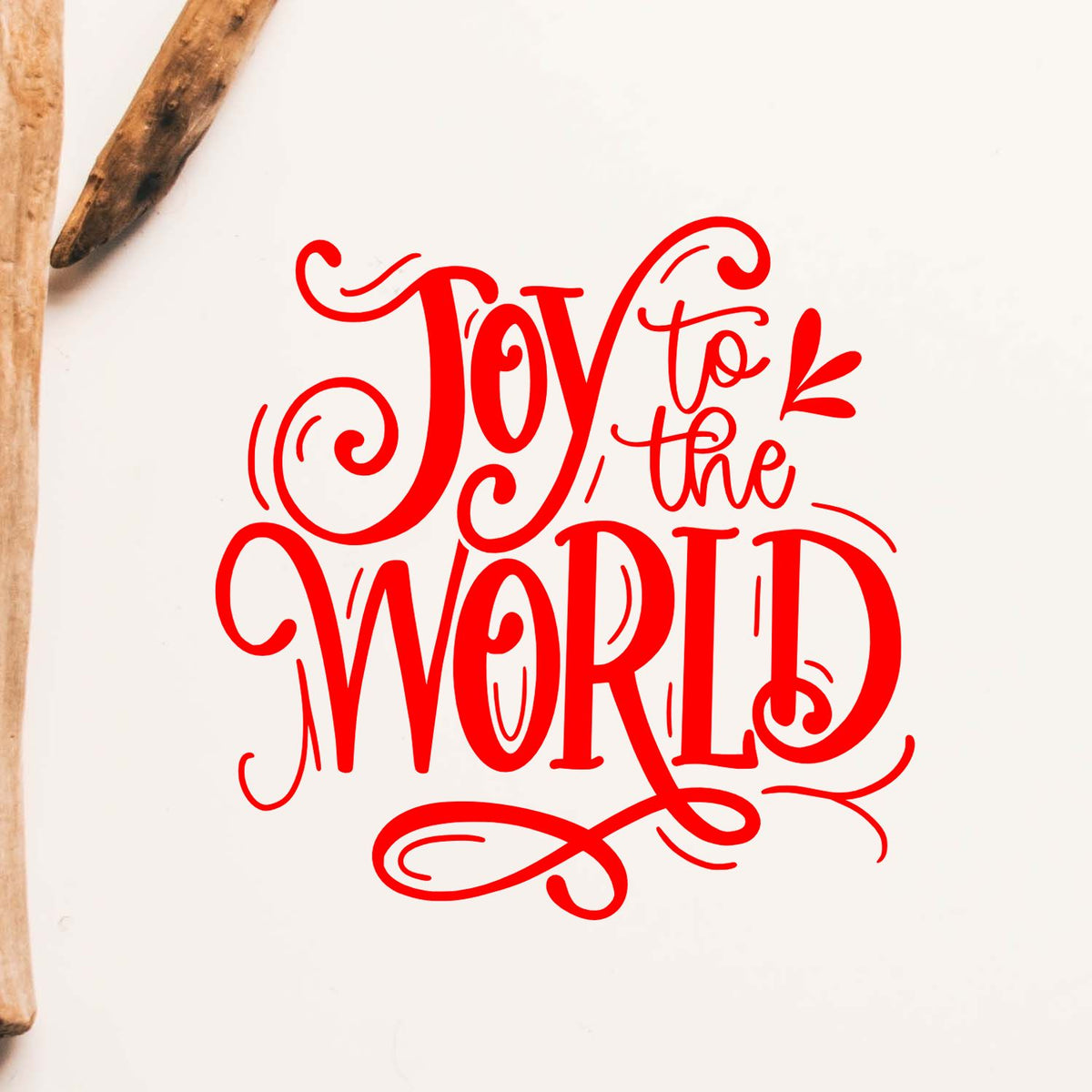 Red decorative stamp and seal design reading Joy to the World, with wooden tools on a white background.