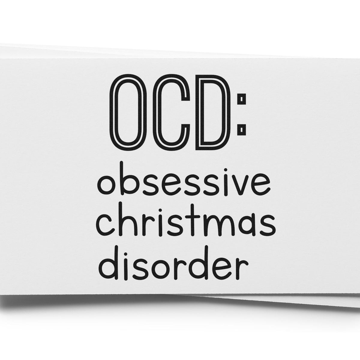 Black self-inking stamp reading OCD: obsessive christmas disorder in bold black text on white paper.