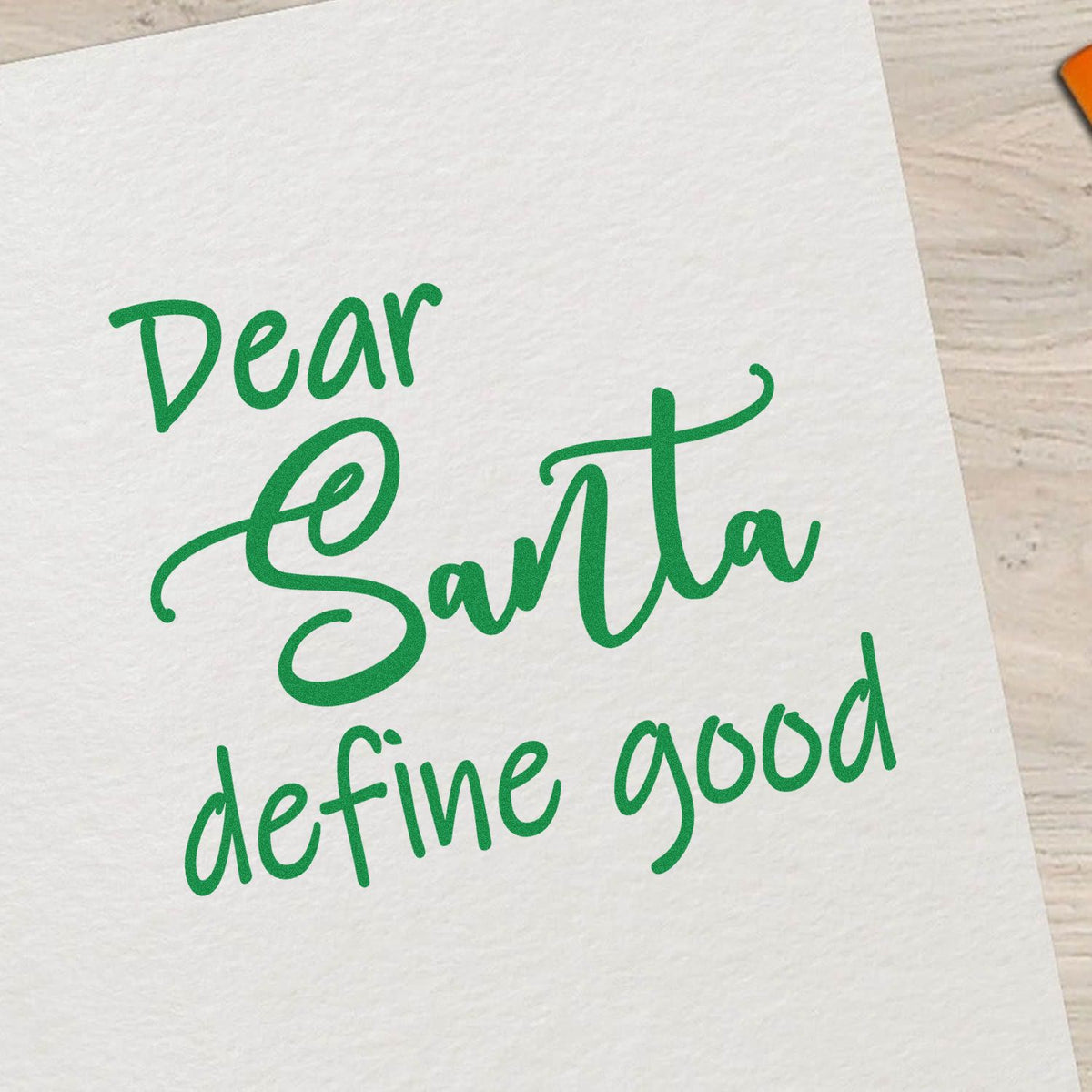 Green custom stamp and seal reading Dear Santa define good on white paper in playful script.