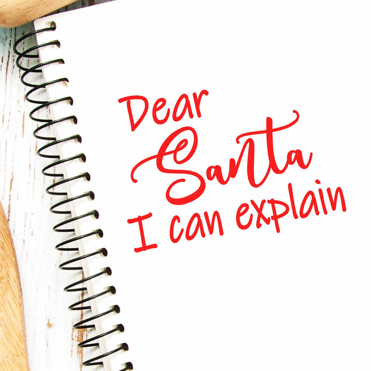 Red holiday stamp and seal design with Dear Santa I can explain on a white spiral notebook page.