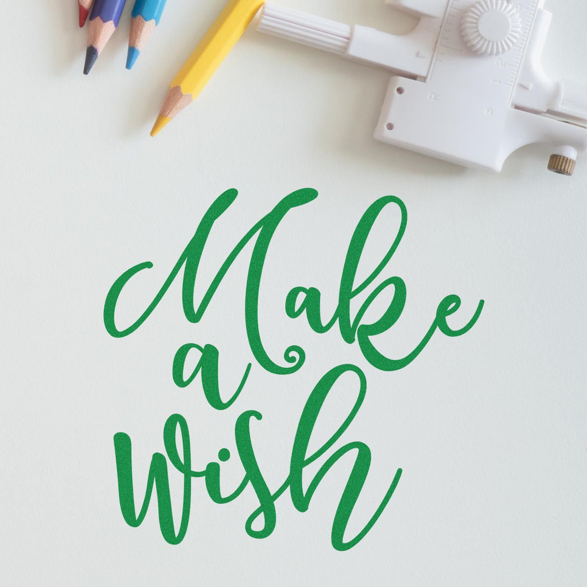 Green cursive Make a Wish stamp with white seal tool and colored pencils on a white background.