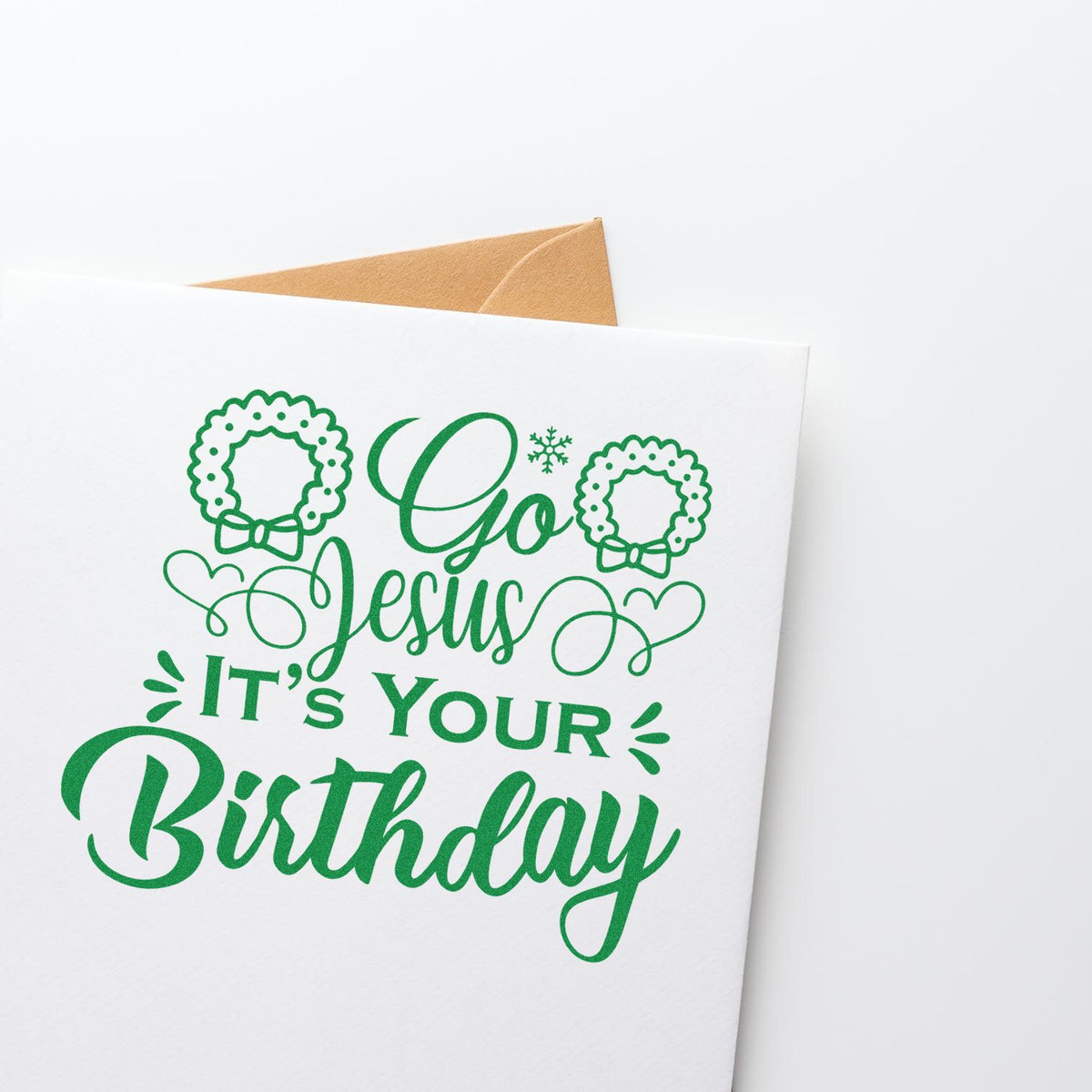 Green custom stamp design on white card reading Go Jesus Its Your Birthday, with wreaths, hearts, and a tan envelope.