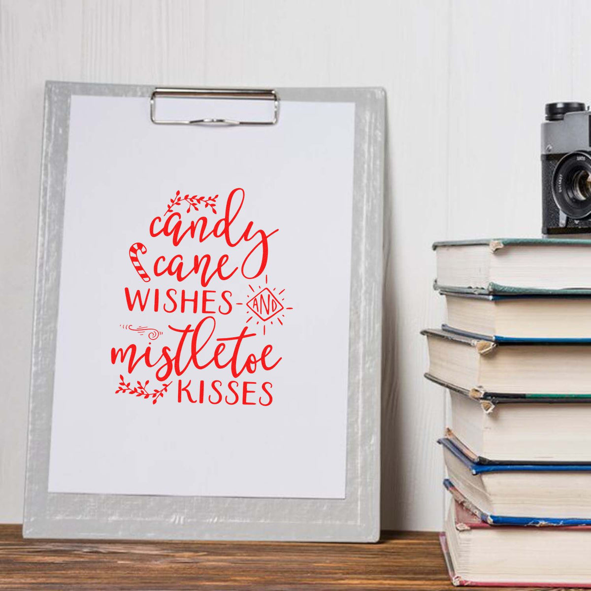 Red Christmas stamp/seal design on white clipboard, reading candy cane wishes and mistletoe kisses.