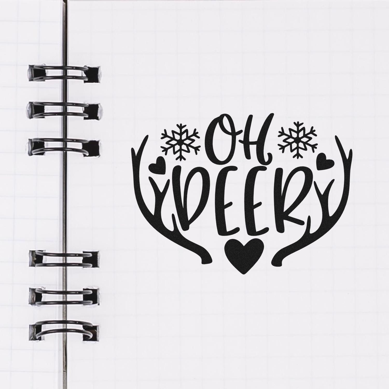 Black OH DEER stamp and seal with antlers, snowflakes, and hearts on white notebook paper with spiral binding.