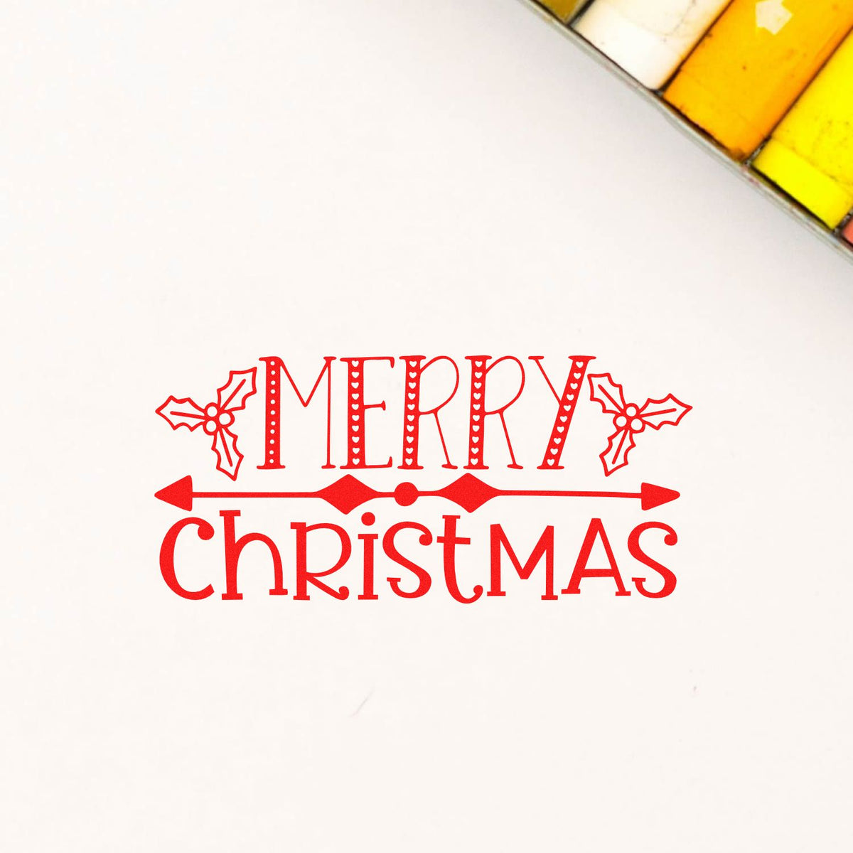 Red Merry Christmas rubber stamp with holly accents and decorative seal details on a white background.