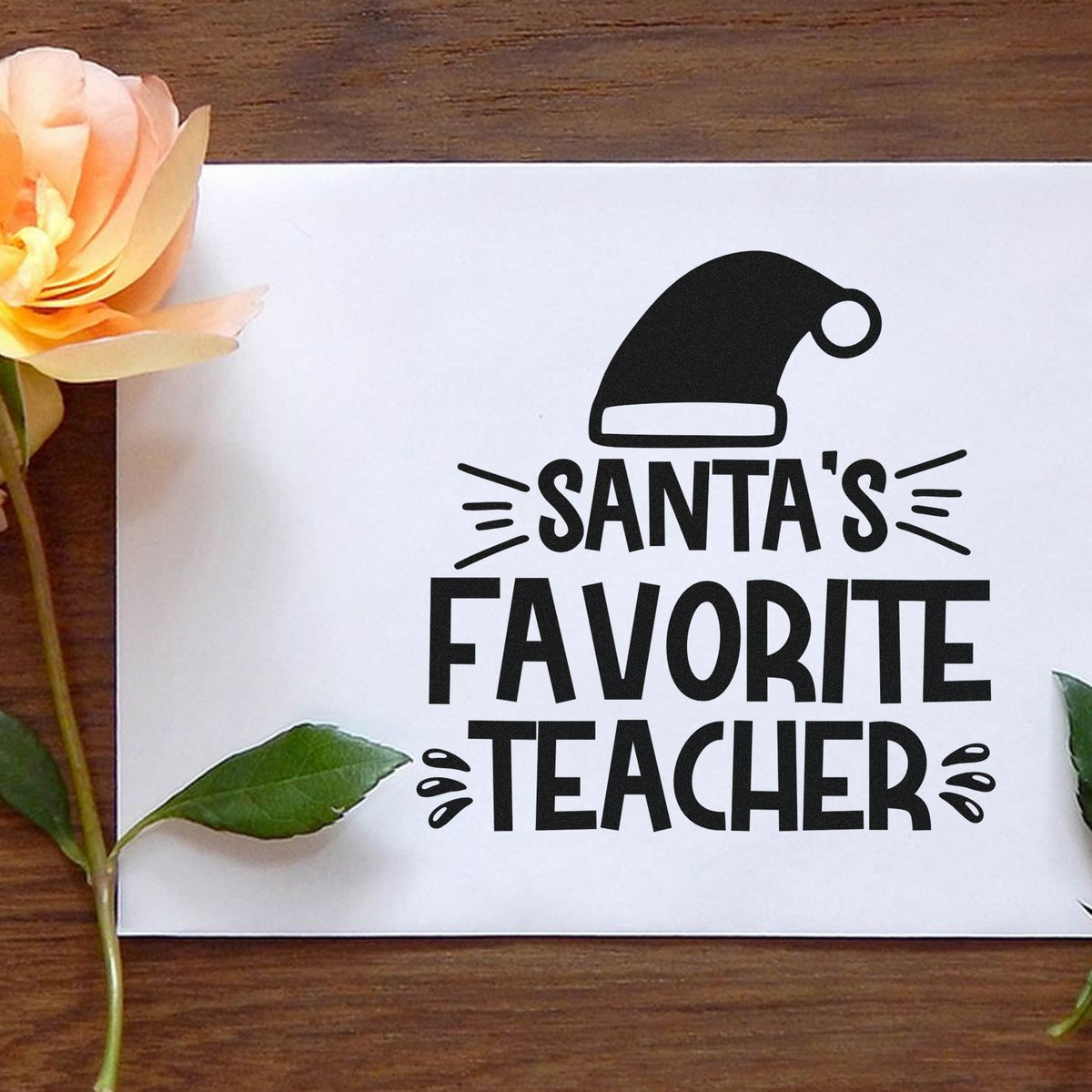 Black Santa hat stamp with bold Santas Favorite Teacher text on white paper, a holiday seal design for teachers.