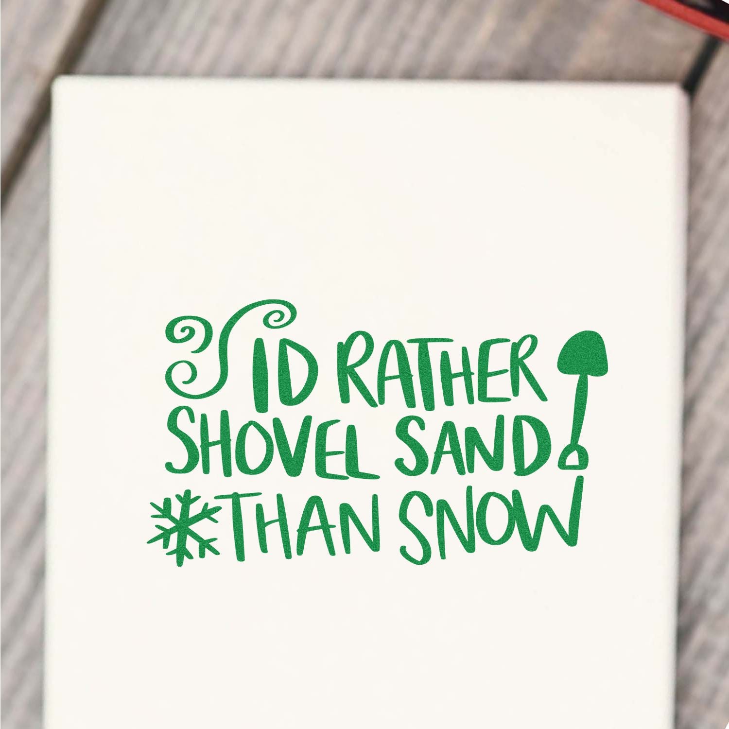 Green Id rather shovel sand than snow stamp design with shovel and snowflake on a white background.