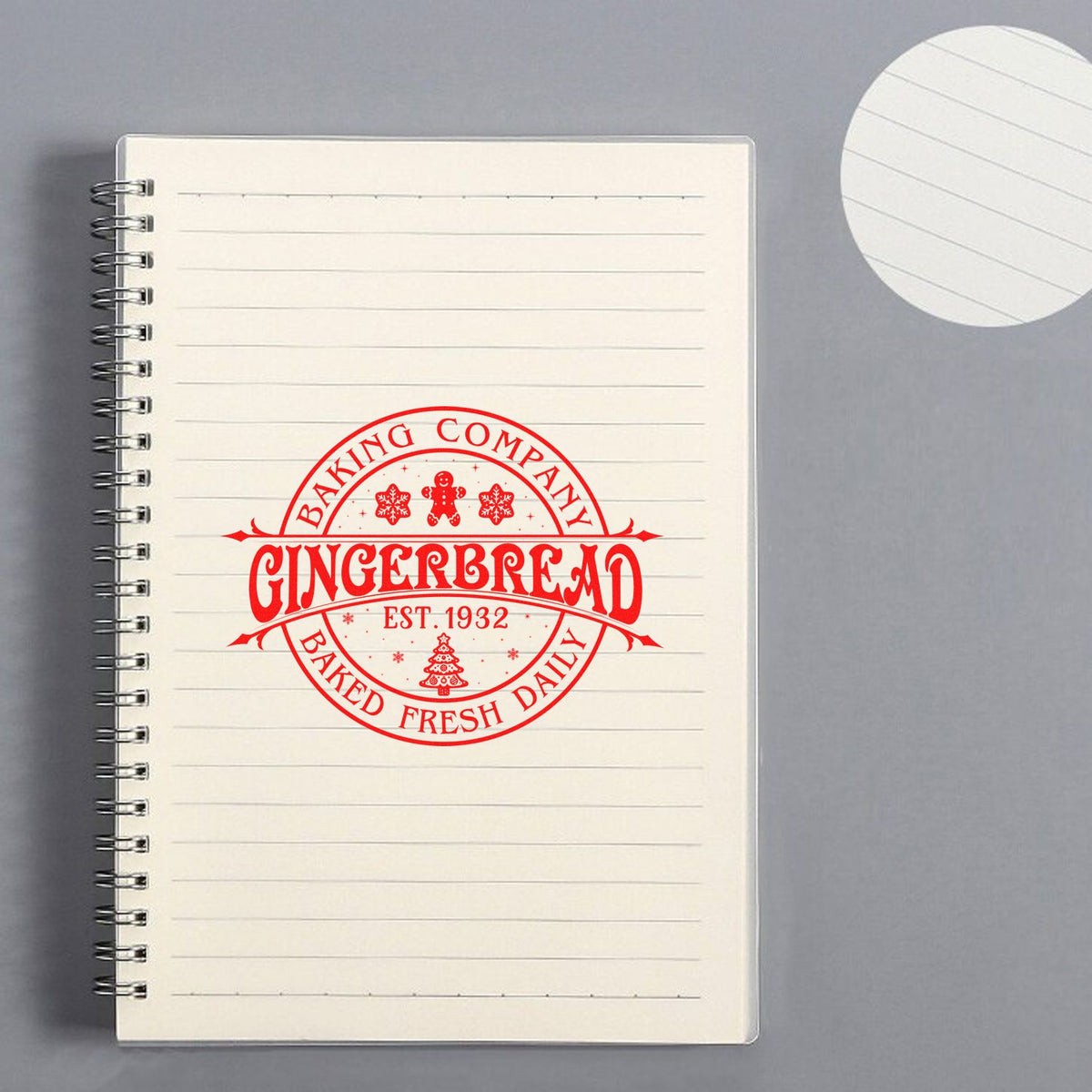 Red gingerbread bakery stamp seal on cream lined notebook, with Baked Fresh Daily, snowflakes, and festive red lettering.