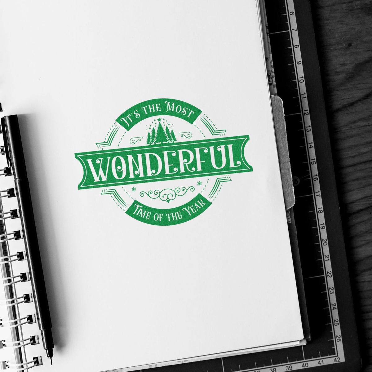 Green vintage-style stamp seal on white paper reading Its the Most Wonderful Time of the Year with pine trees.
