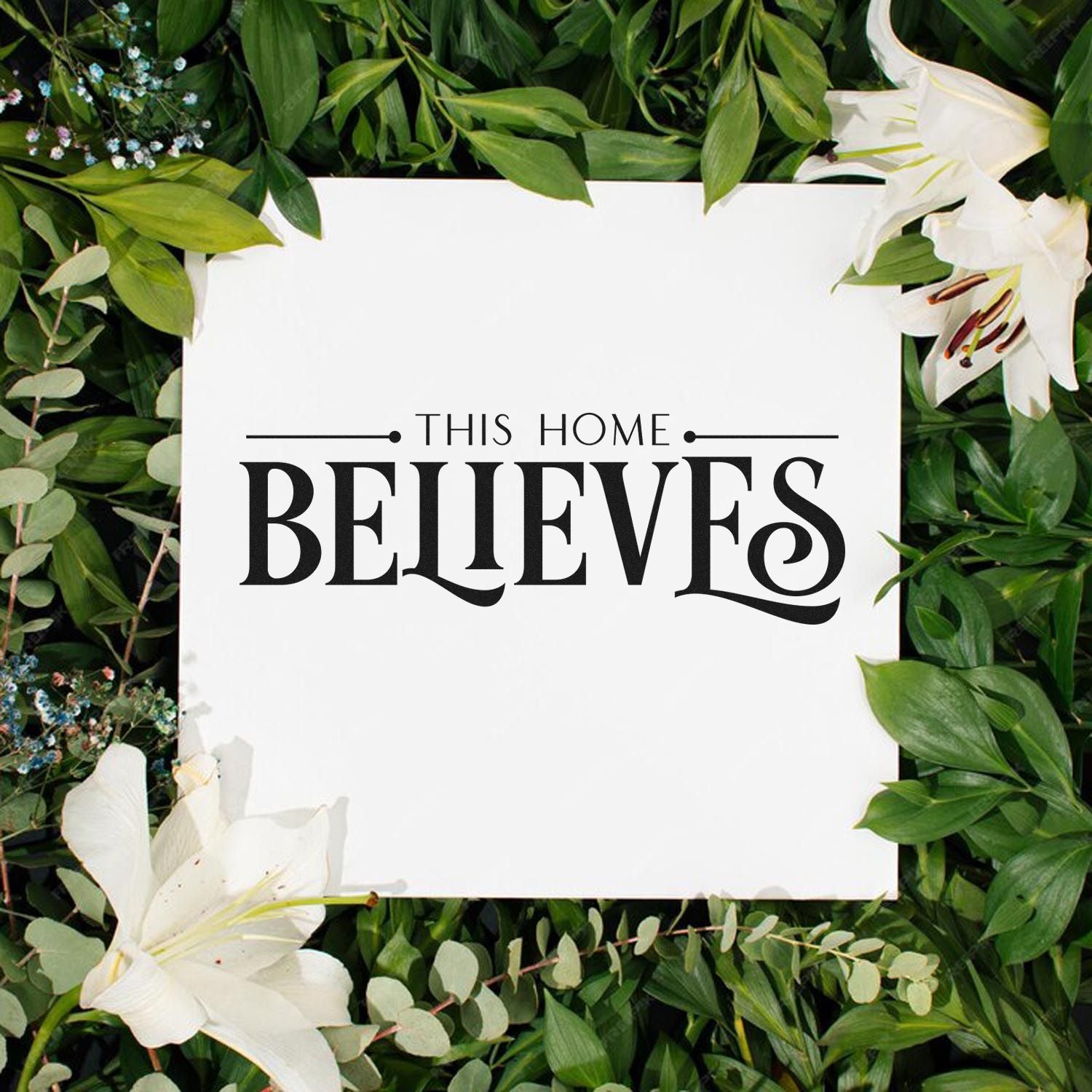 Custom stamp and seal product with black This Home Believes text on a white square, framed by green leaves and white lilies.