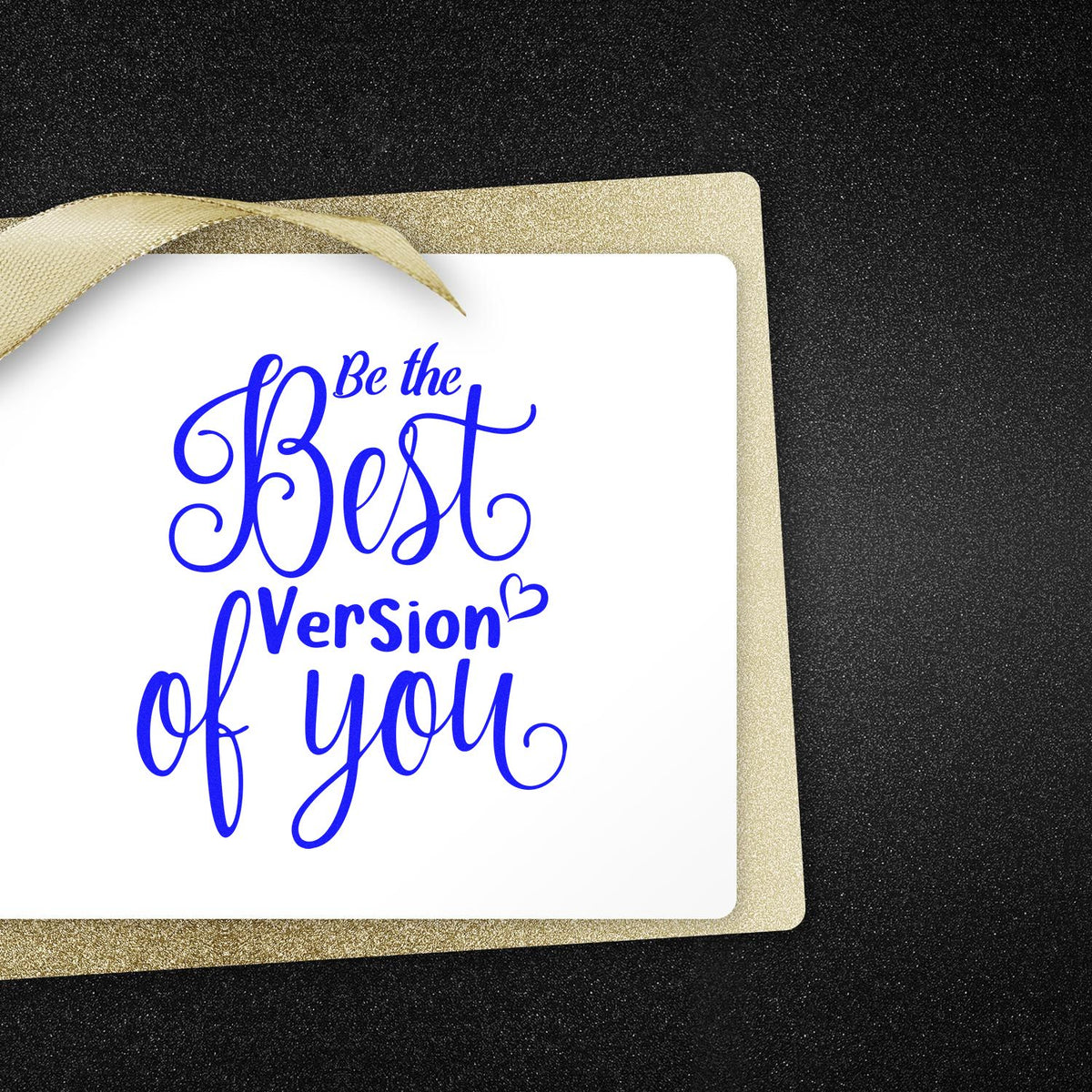 Blue stamp and seal reading Be the Best Version of You on white card with gold glitter border and ribbon, black background.