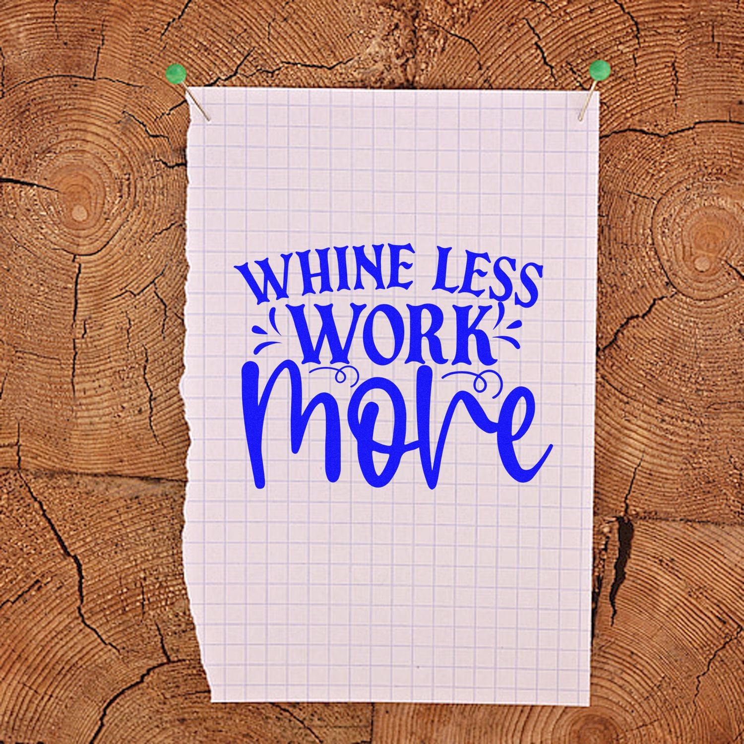 Blue stamp and seal design reading Whine Less Work More on white graph paper pinned to rustic wood.
