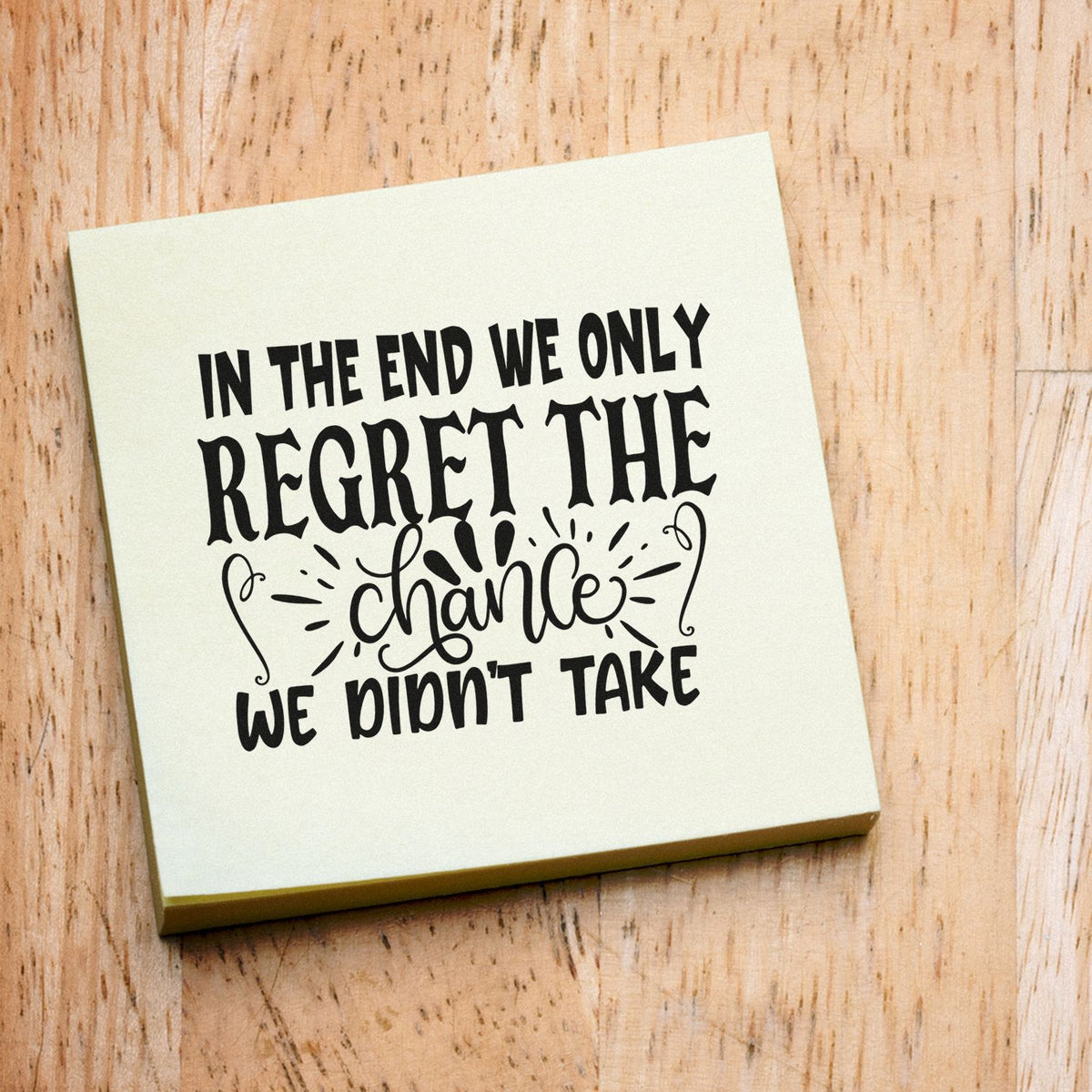 Cream stamp and seal block with black quote lettering on wood: In the end we only regret the chance we didnt take.