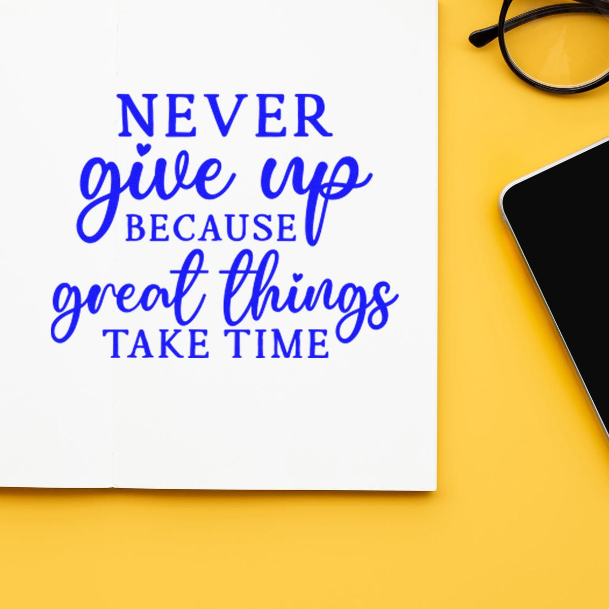 Blue Never give up because great things take time stamp and seal on white paper, with yellow background, glasses and phone.