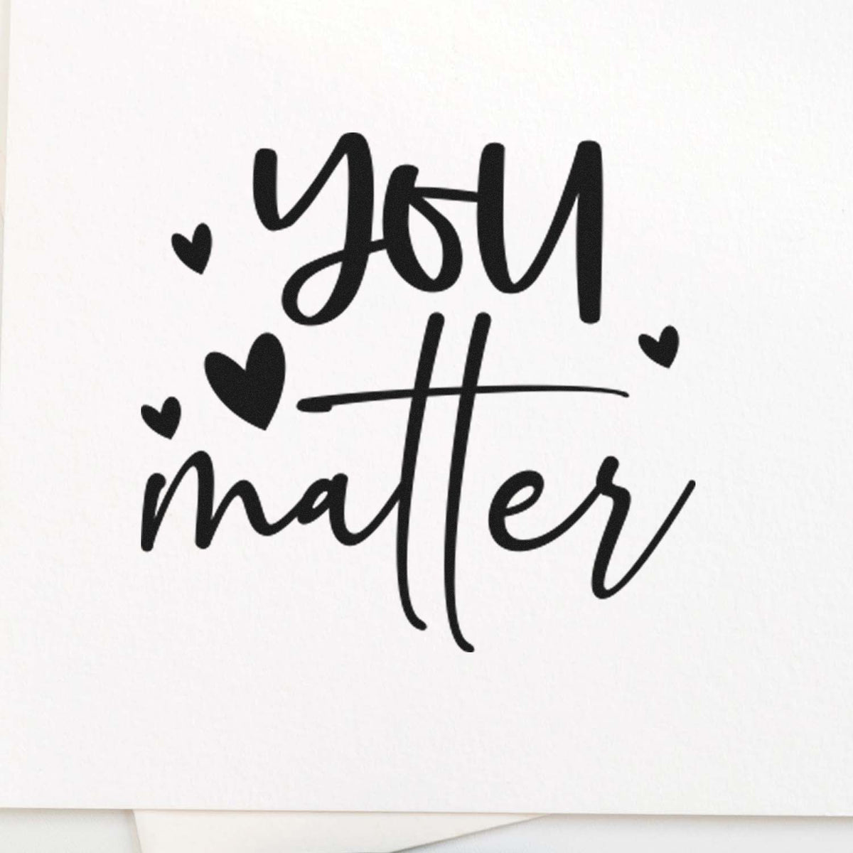 You Matter Scattered Hearts Script Lettering Premium Wooden Stamp - Vintage Pro imprint stamped in black ink. The words "You matter" appear in large casual script surrounded by solid hearts.