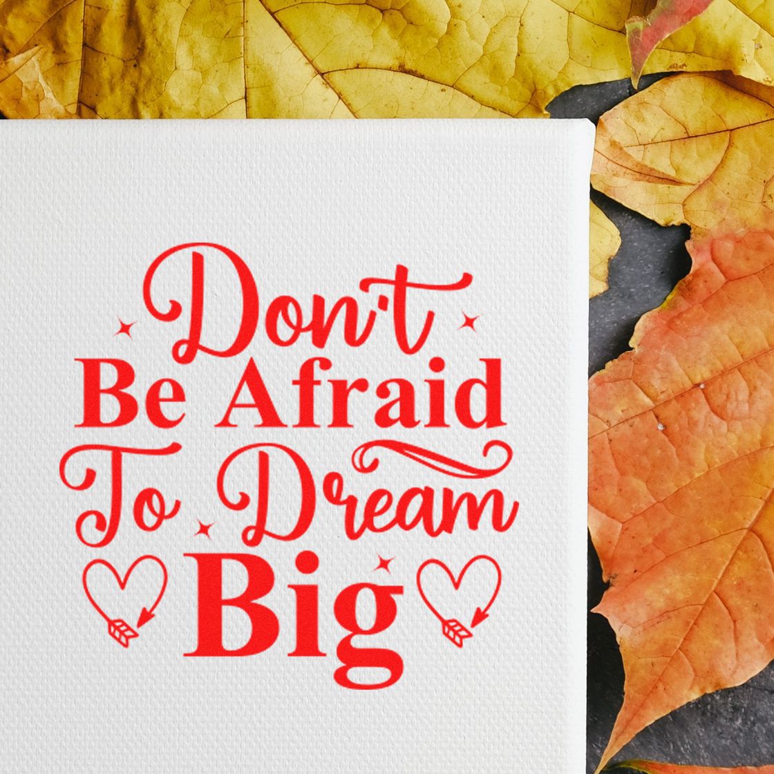 White stamp and seal product with red Dont Be Afraid To Dream Big lettering, framed by autumn leaves.