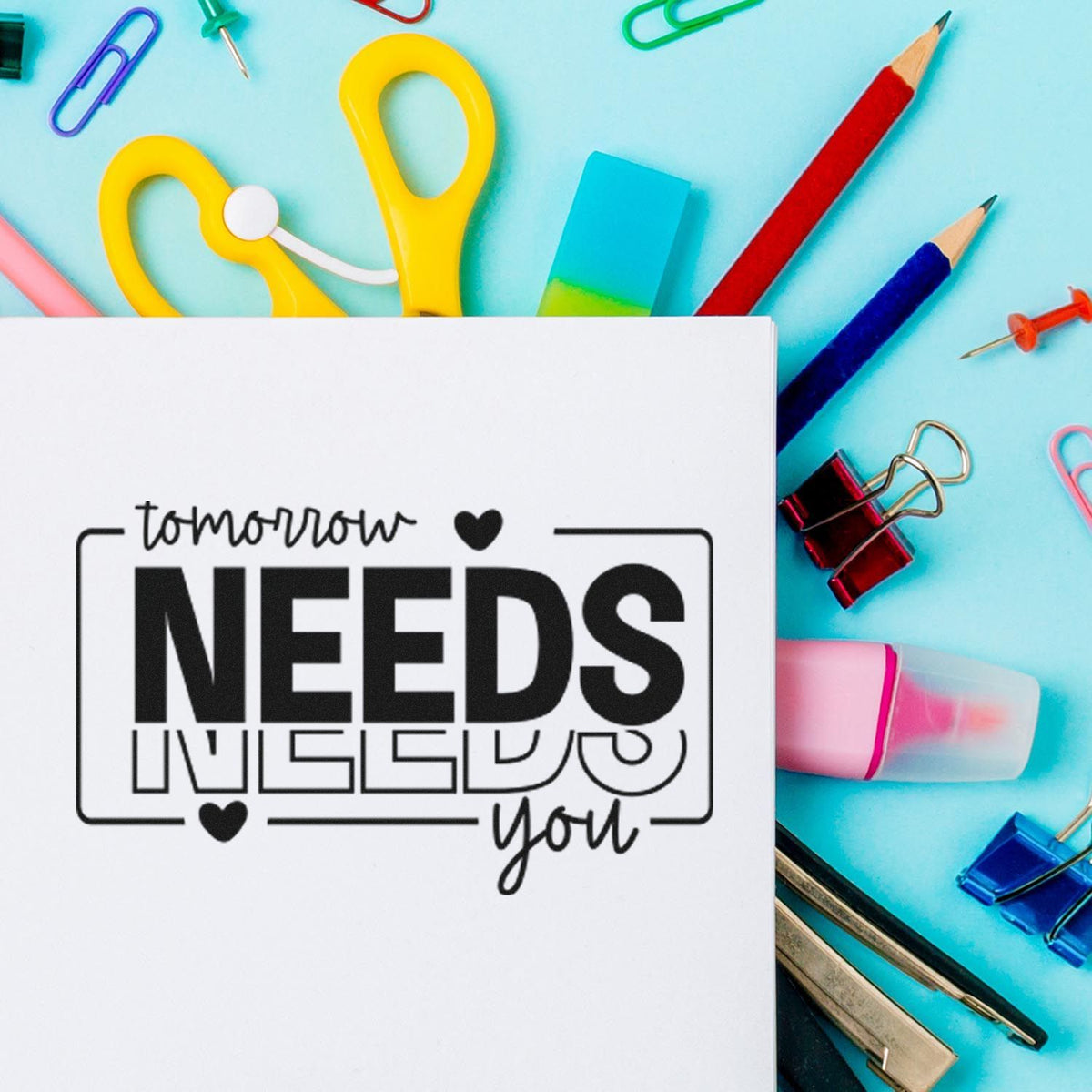 Tomorrow Needs You Repeated With Hearts Slim Pre-Inked Stamp imprint stamped in black ink. The words "tomorrow needs you" appear in an open rectangular frame with repeated solid and outlined "needs" lettering and hearts.