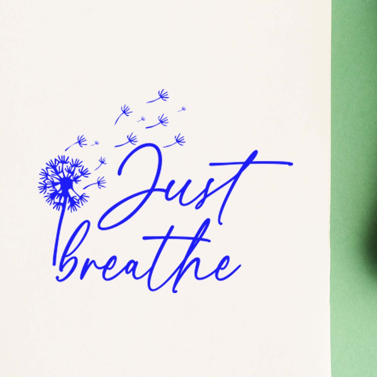 Blue Just breathe dandelion rubber stamp and seal on white paper with green edge.