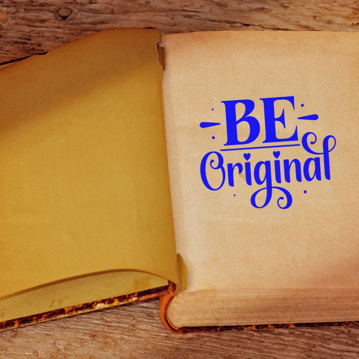 Blue BE Original stamp and seal on aged parchment pages in an open vintage book on rustic wood.