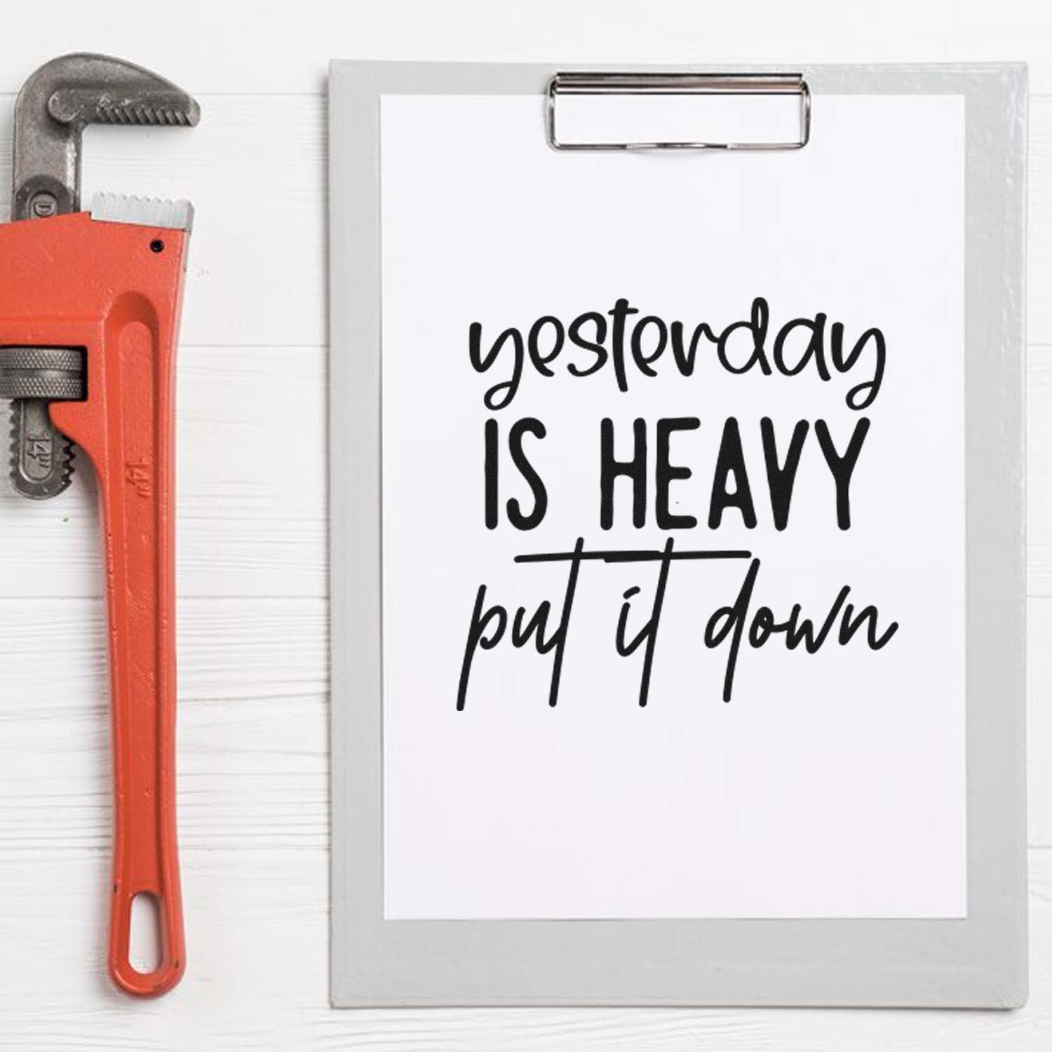 Orange stamp-and-seal tool beside clipboard with black quote yesterday is heavy put it down on white background.
