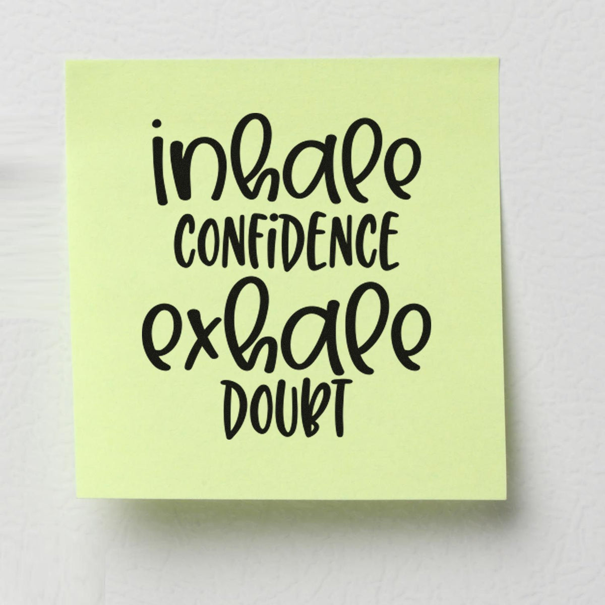 Pale yellow stamp seal with black handwritten text reading inhale confidence exhale doubt.