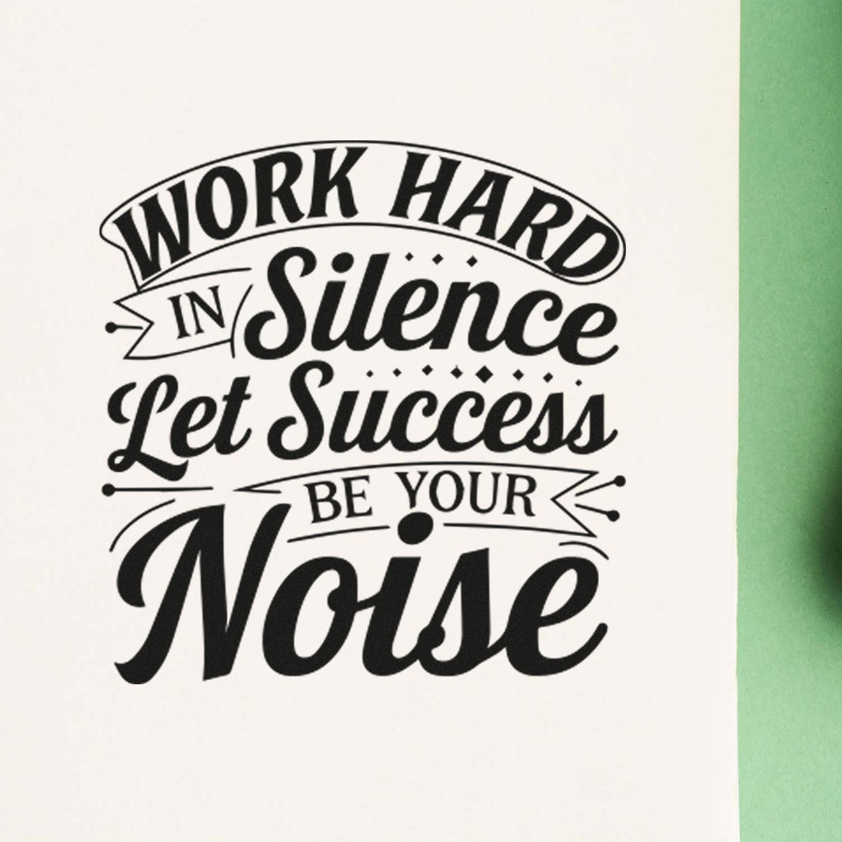 Black decorative stamp seal on white paper with green edge, reading Work Hard in Silence, Let Success Be Your Noise.