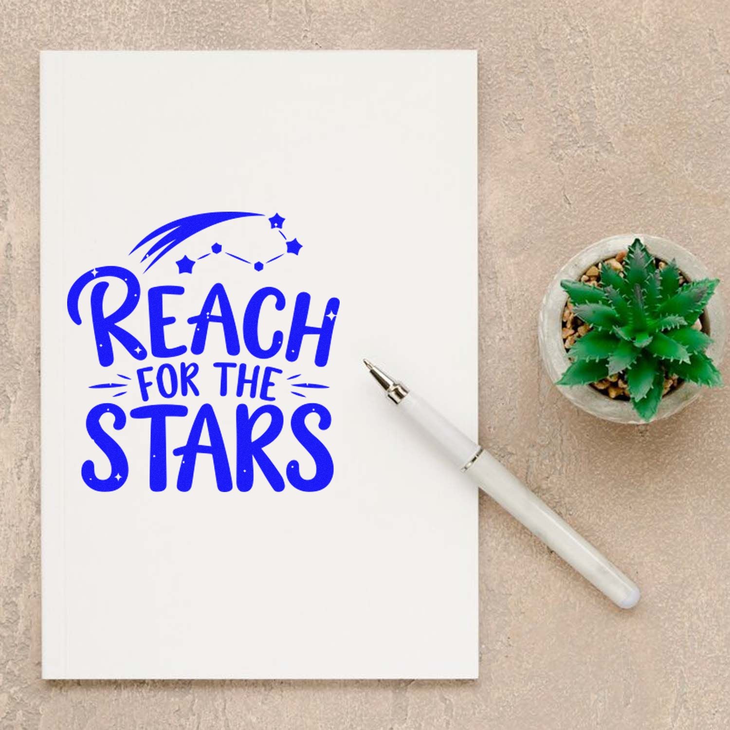 Blue Reach for the Stars custom stamp seal on white paper, with constellation stars, white pen, and green succulent.