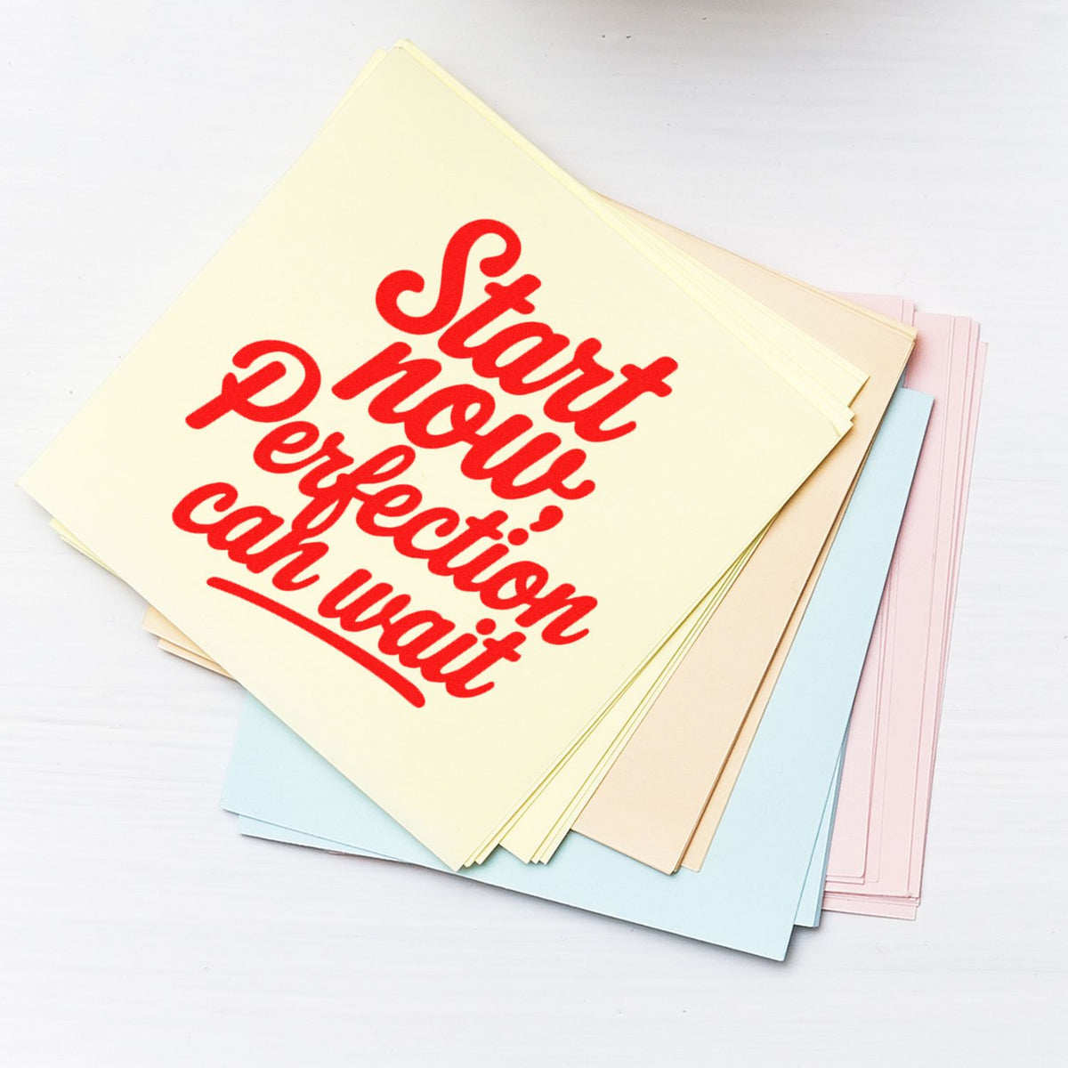 Pastel stamp and seal sheets stacked on white, featuring bold red Start now, perfection can wait lettering.