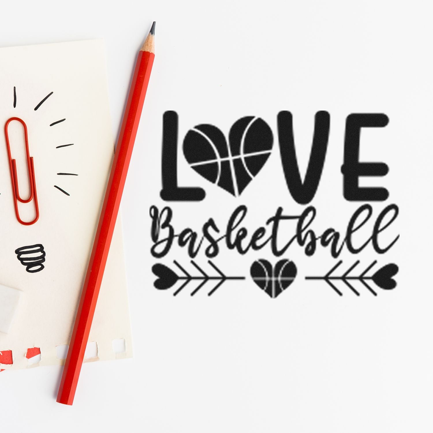 Black LOVE basketball stamp and seal design with heart-ball, cursive Basketball, on white paper beside a red pencil