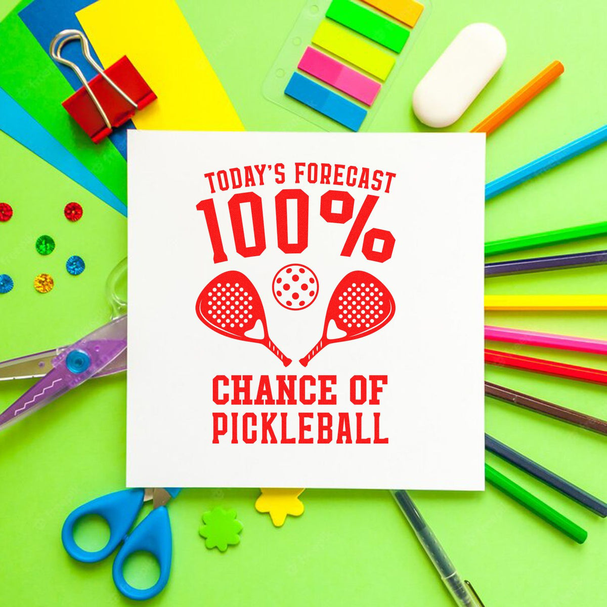 White stamp-and-seal card with red 100% chance of pickleball text, paddle icons, and colorful stationery on green background.