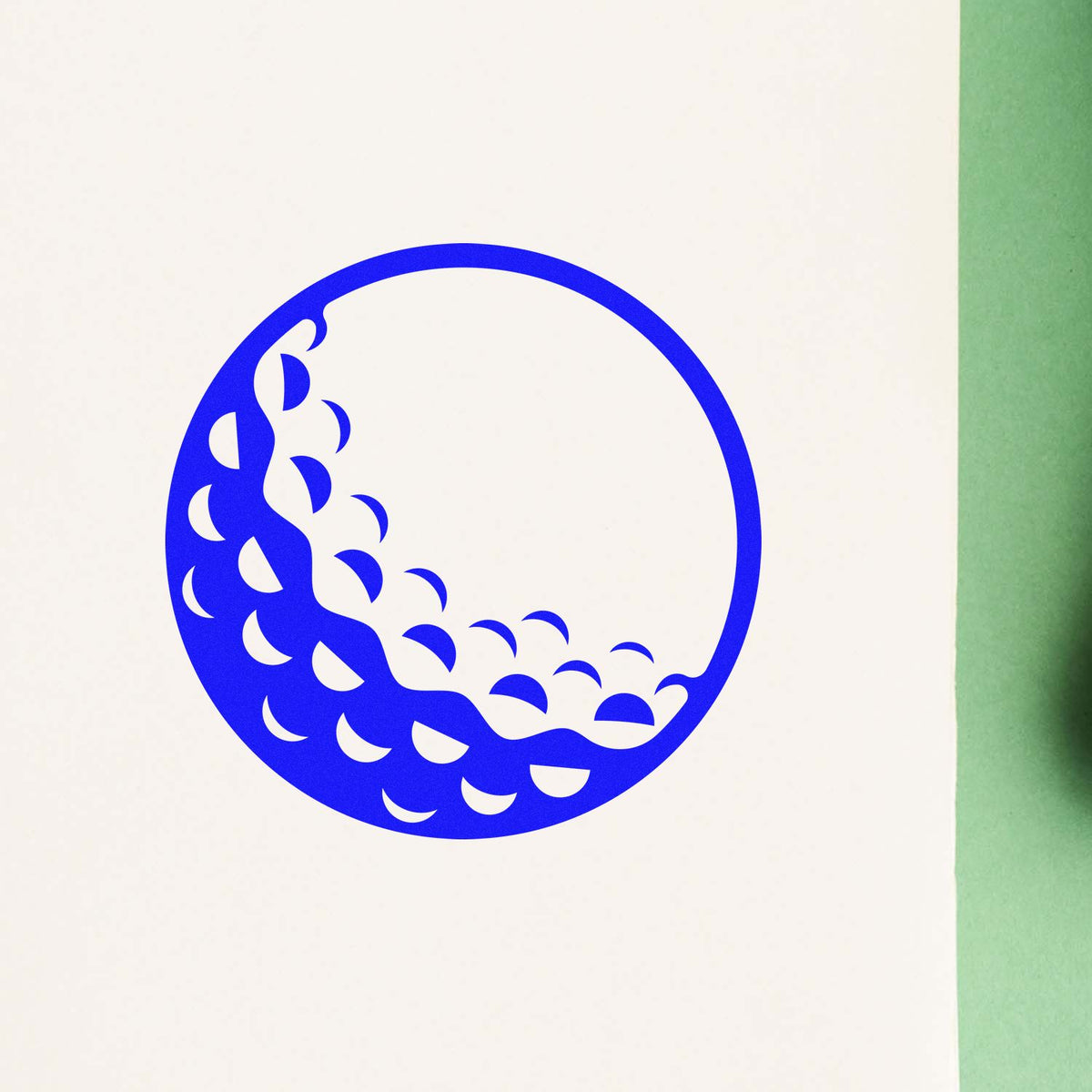 Blue circular stamp seal with crescent cutouts on off-white paper, beside a green edge.