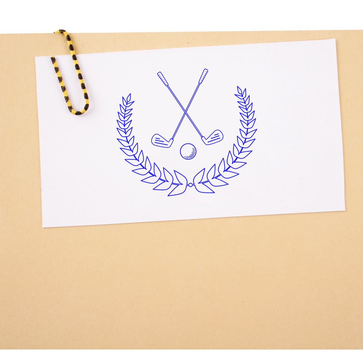 Blue golf stamp and seal product with crossed clubs, golf ball and laurel wreath on white paper, clipped to beige board.