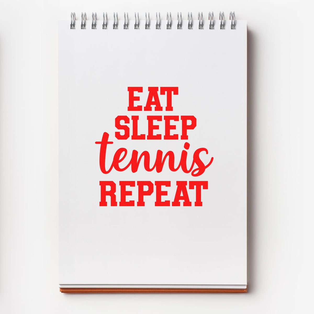 Red custom stamp and seal design on a white spiral notebook, reading EAT SLEEP tennis REPEAT in bold and script text.