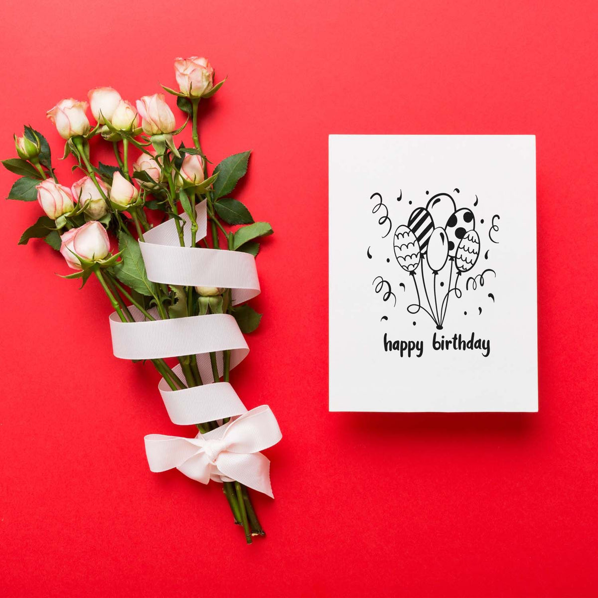 Pink roses with white ribbon beside a white birthday stamp and seal card on a bright red background.