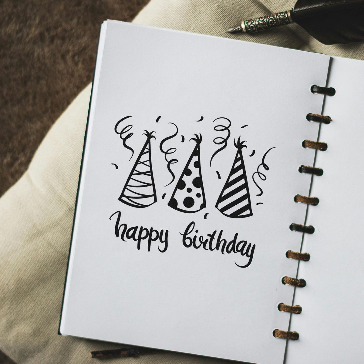 Three Patterned Birthday Party Hats Premium Wooden Stamp - Vintage Pro imprint stamped in black ink. Three patterned party hats sit above happy birthday surrounded by curling streamers.