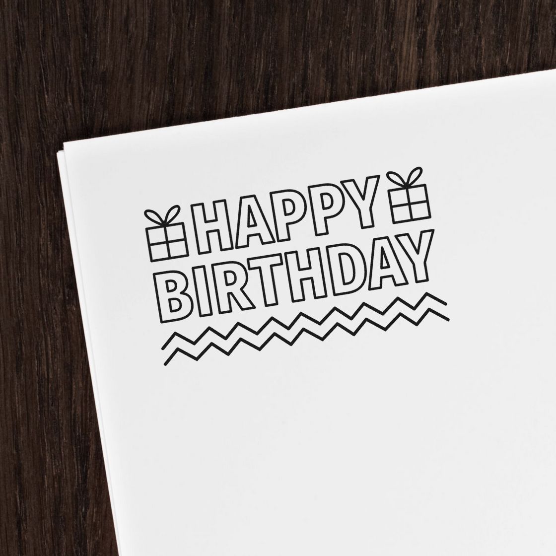 Black Happy Birthday stamp and seal design with gift icons and zigzag border on white paper.