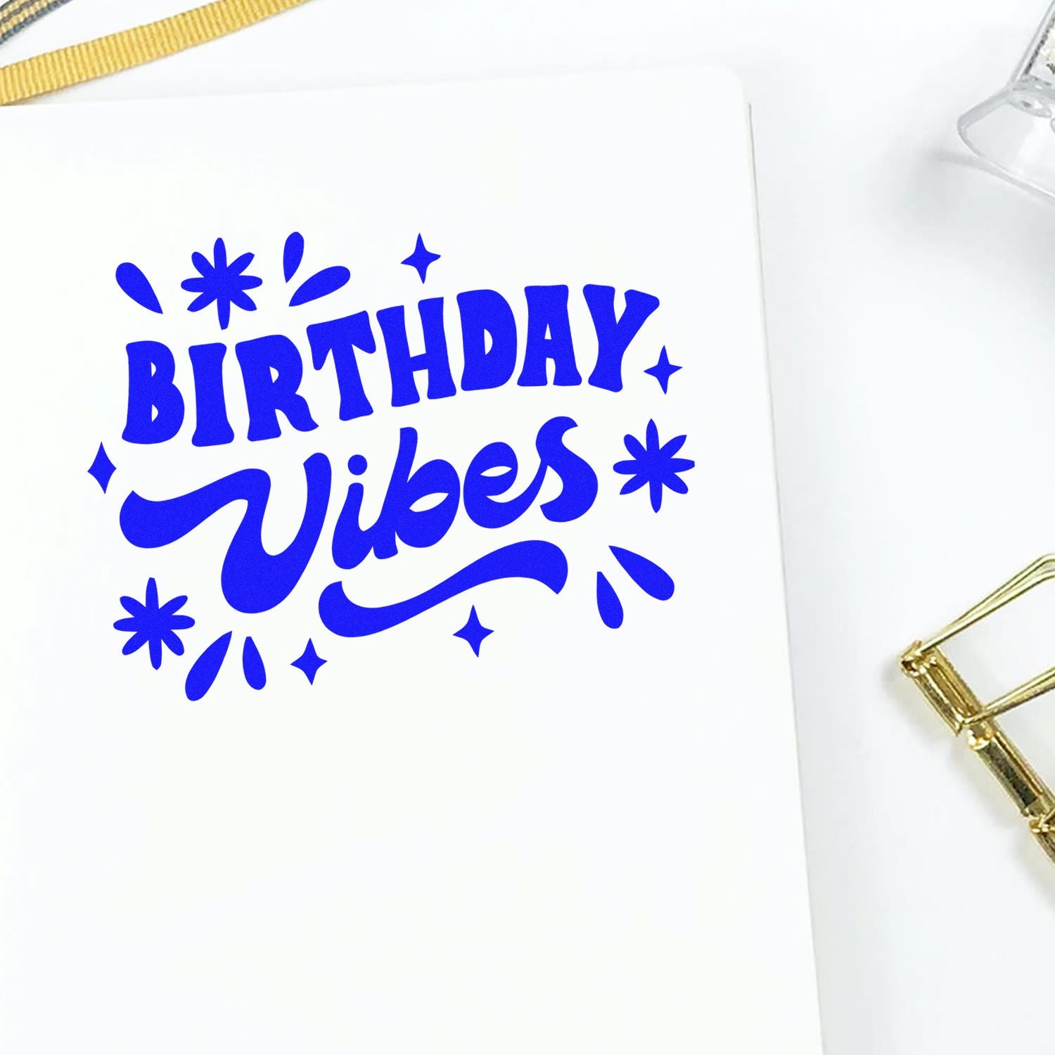 Blue Birthday Vibes stamp seal with playful star accents on white paper, with gold office details.