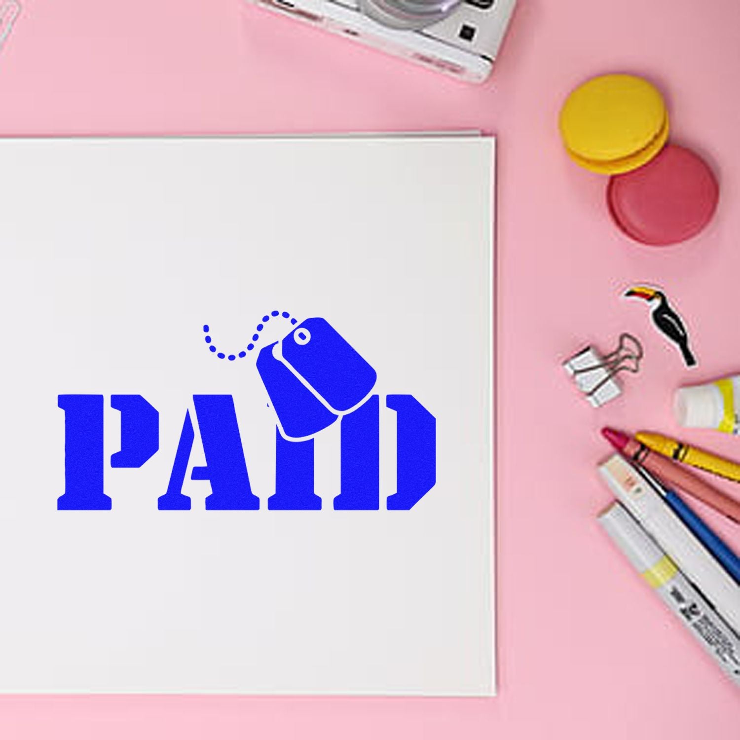 White card with blue PAID stamp and tag icon on pink background, surrounded by colorful stamp and seal tools.